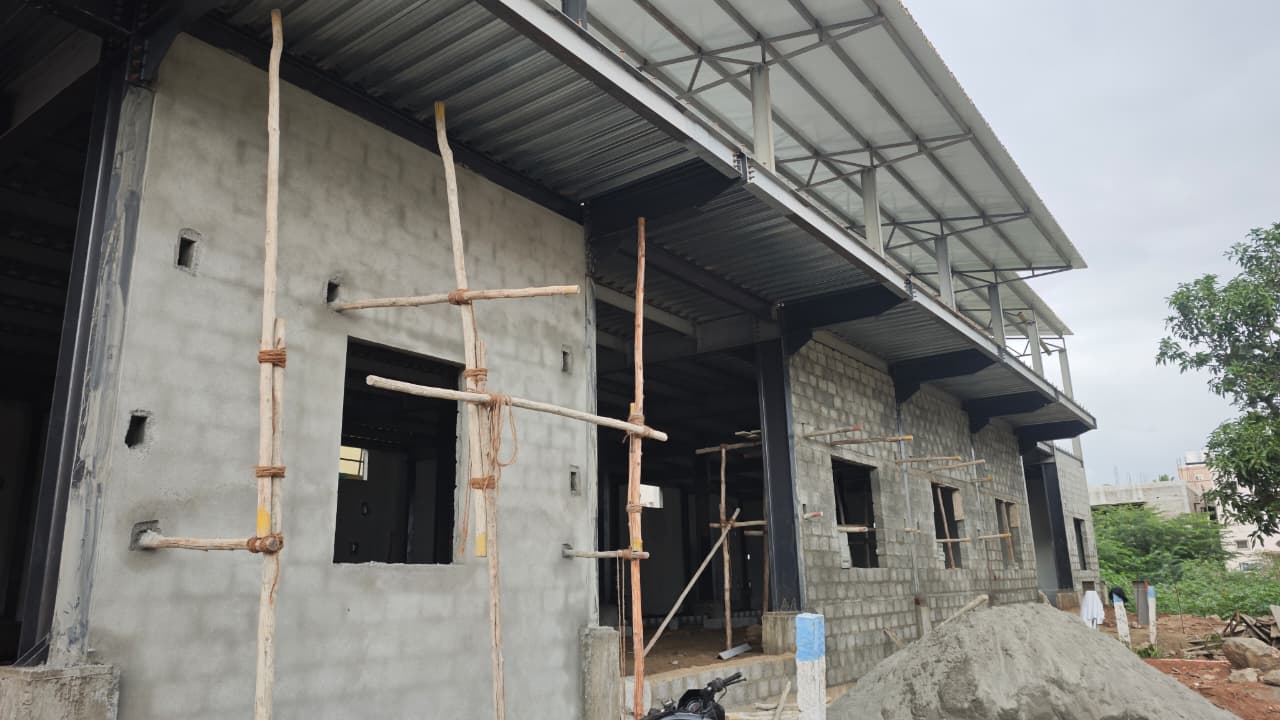 Steel frame construction site with workers and sand piles