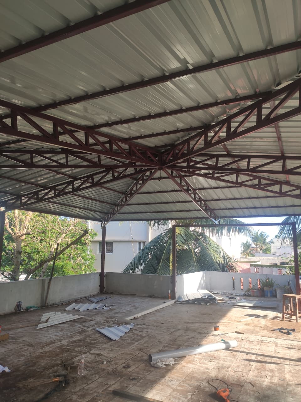 Finished steel canopy structure on a rooftop terrace with palm trees