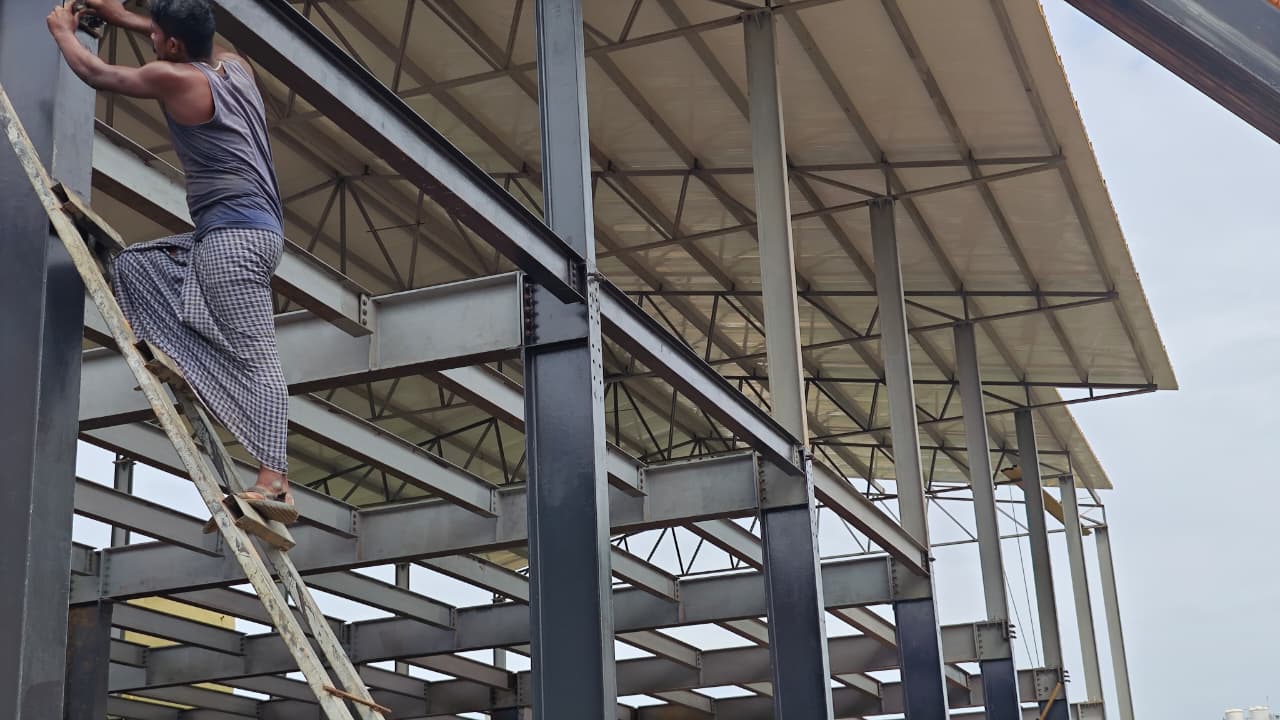 Worker on a ladder installing steel roof framing