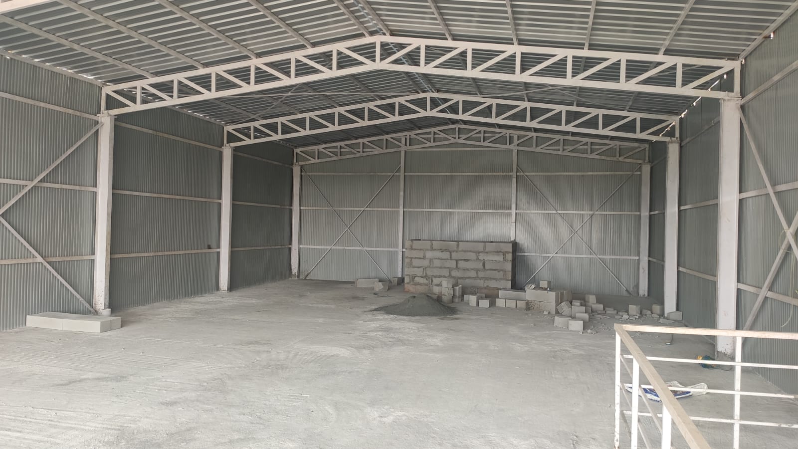 Empty steel-framed warehouse interior with block wall accent