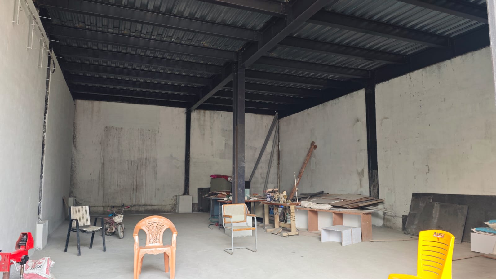 Interior view of a steel-framed structure with construction tools and furniture