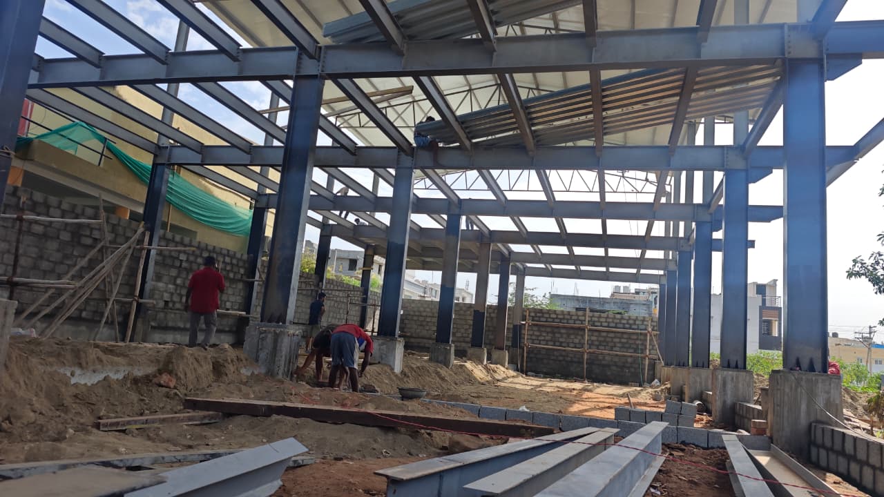 Workers installing steel roof framing on a construction site